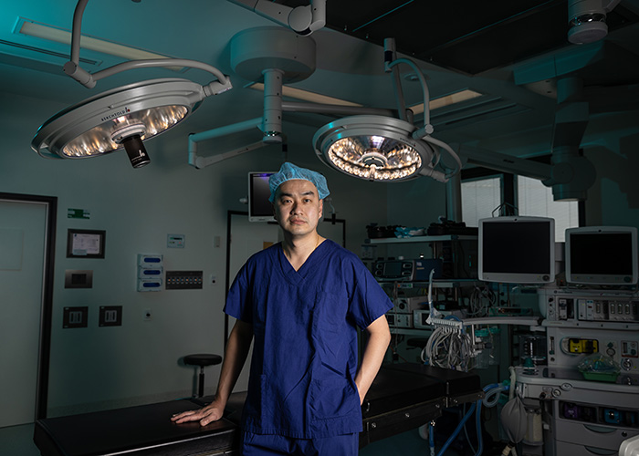 Keat Ooi posing in an operating theatre before performing ACDF Surgery